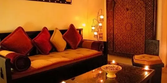Le salon de repos : banquette basse, coussins rouges, bougies